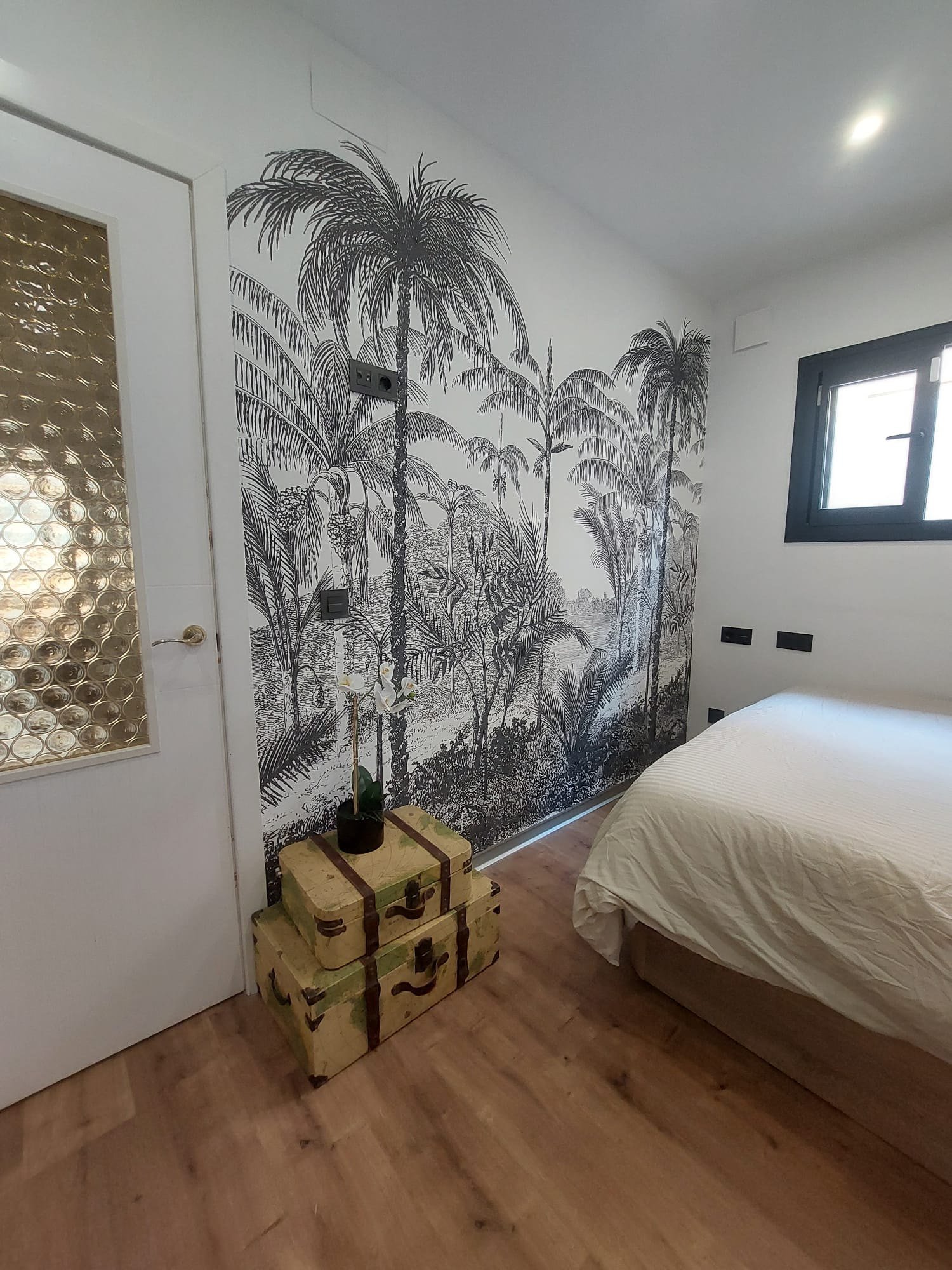 Mural de palmeras en blanco y negro instalado en la pared de un dormitorio