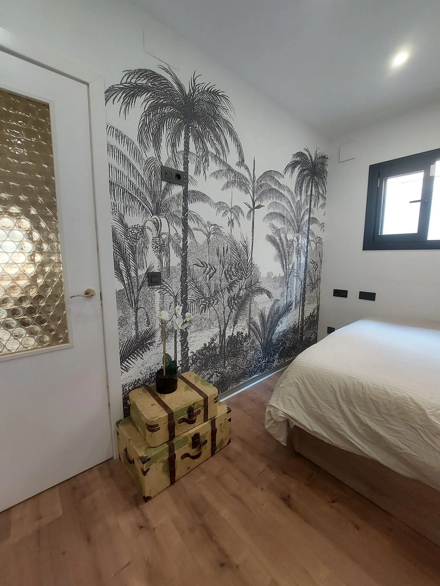 Mural de palmeras en blanco y negro instalado en la pared de un dormitorio