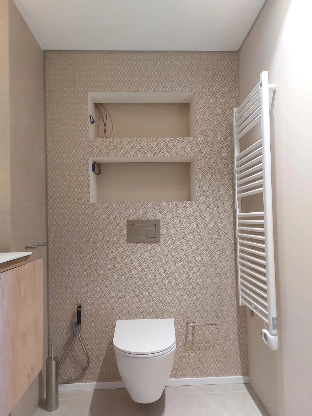 Baño reformado con papel pintado beige texturado y hornacinas de obra