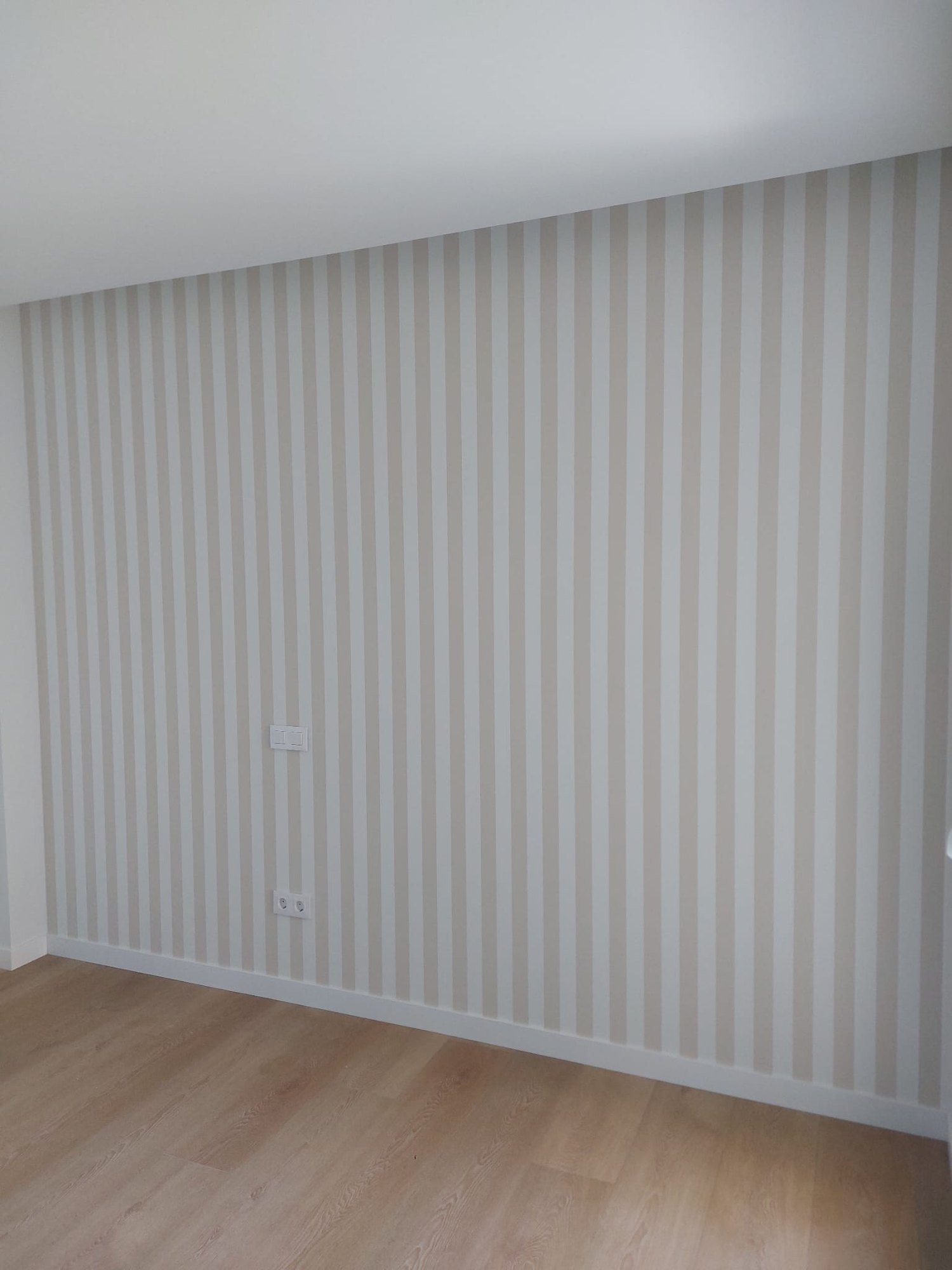 Habitación con papel pintado de rayas beige y suelo de madera