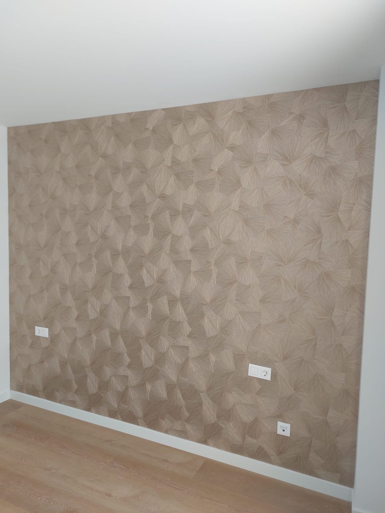 Pared de salón forrada con papel pintado texturado en tono beige