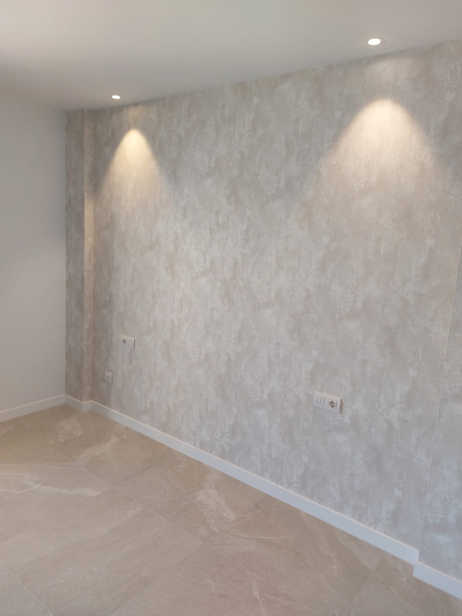 Pared de salón con acabado decorativo tipo estuco en tonos arena