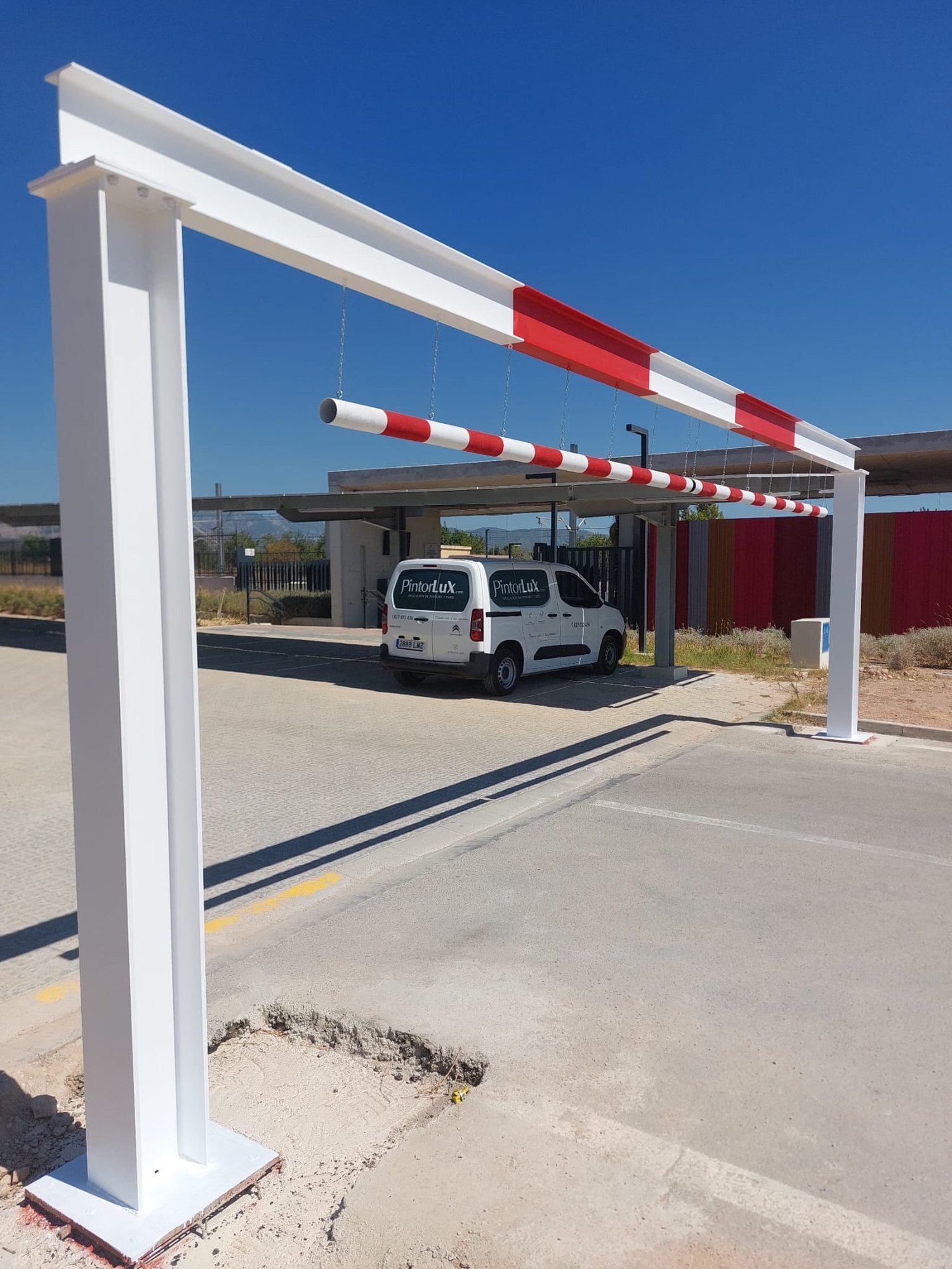 Barrera vial pintada en blanco y rojo junto a la furgoneta de PintorLux