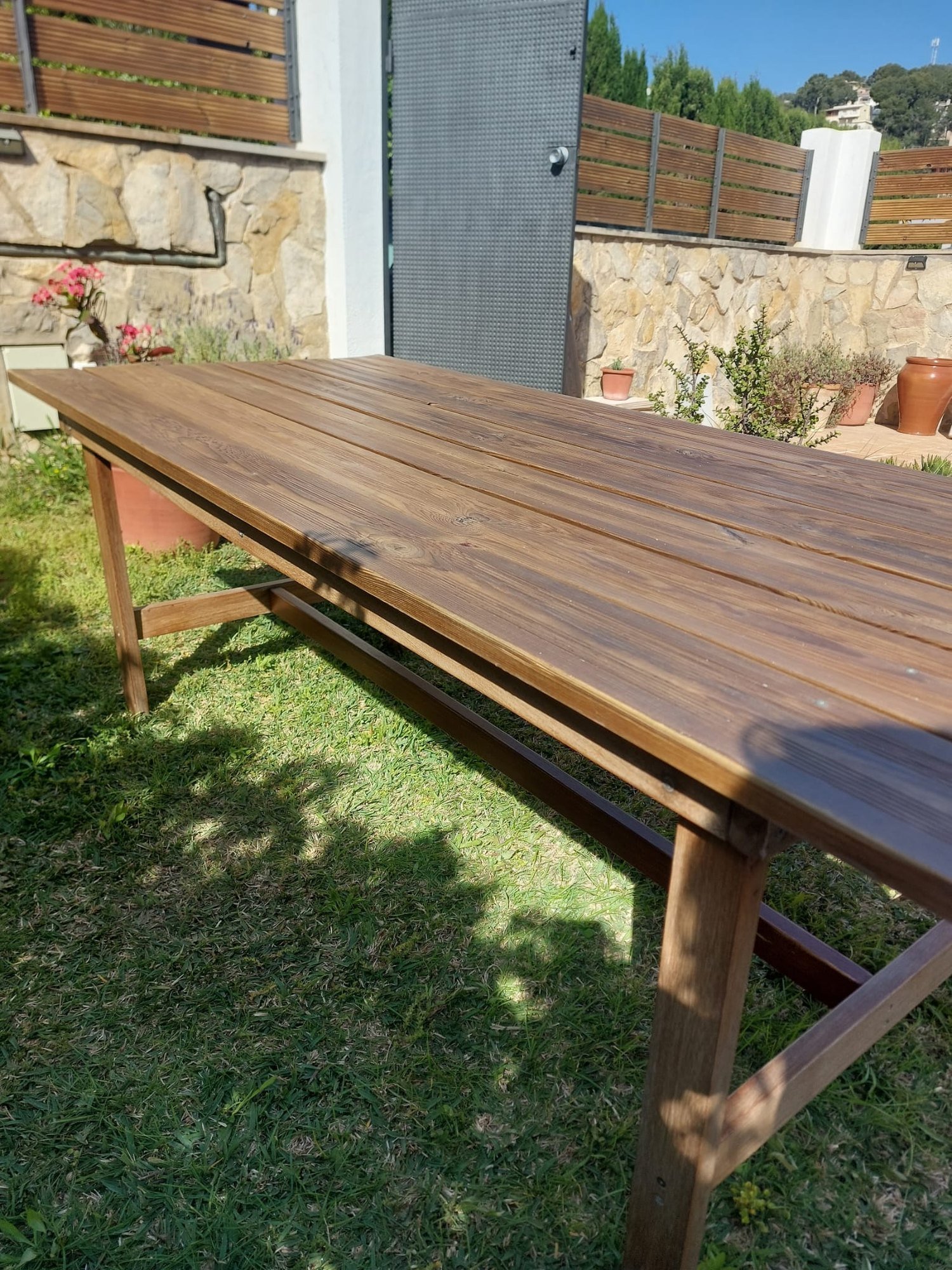 Mesa de madera restaurada y barnizada en el jardín de una vivienda